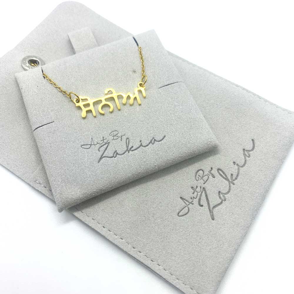 Punjabi name necklace reading “Sonia” in Gurmukhi, placed inside luxury grey velvet packaging