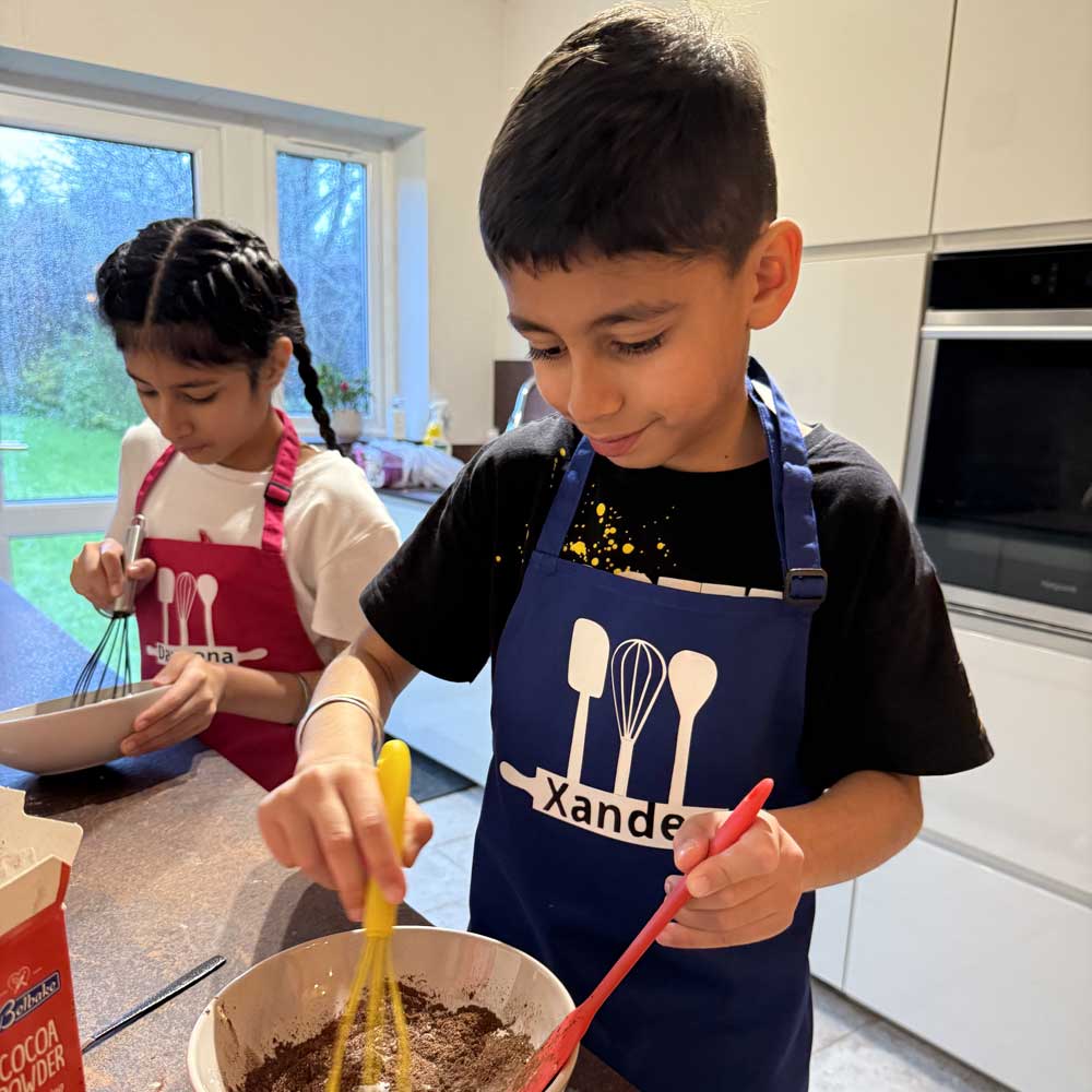 brother and sister wearing personalised aprons for kids with name while baking in kitchen