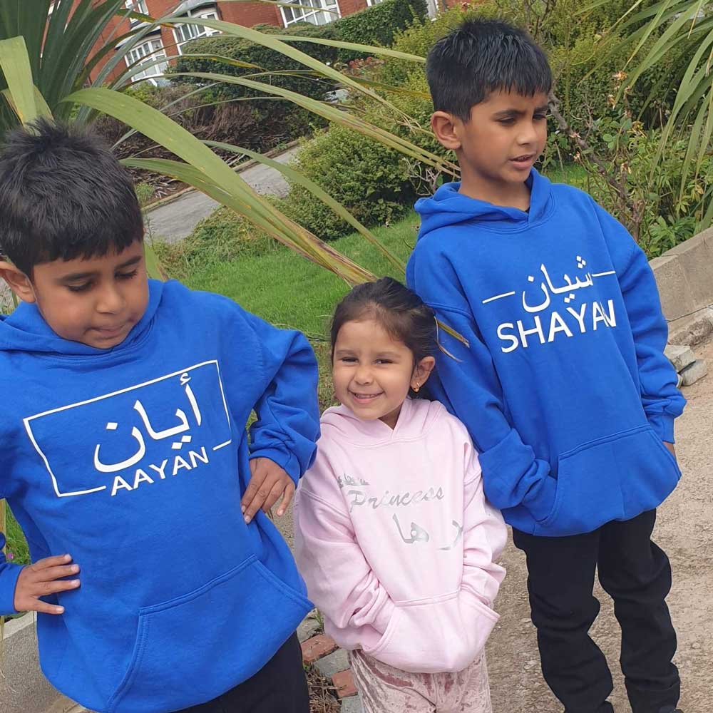 boys and girls wearing personalised hoodie for kids in blue and pink with names in arabic and english