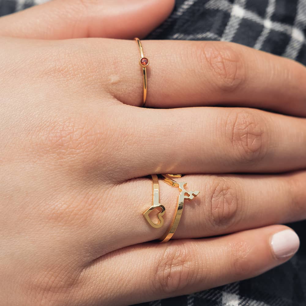 woman wearing twisted initial ring with a open heart on one side and a arabic letter initial on the other side