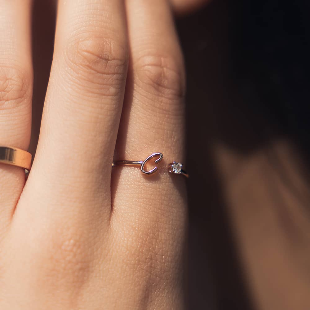 woman wearing rose gold resizable initial ring with letter c and a cubic zirconia stone