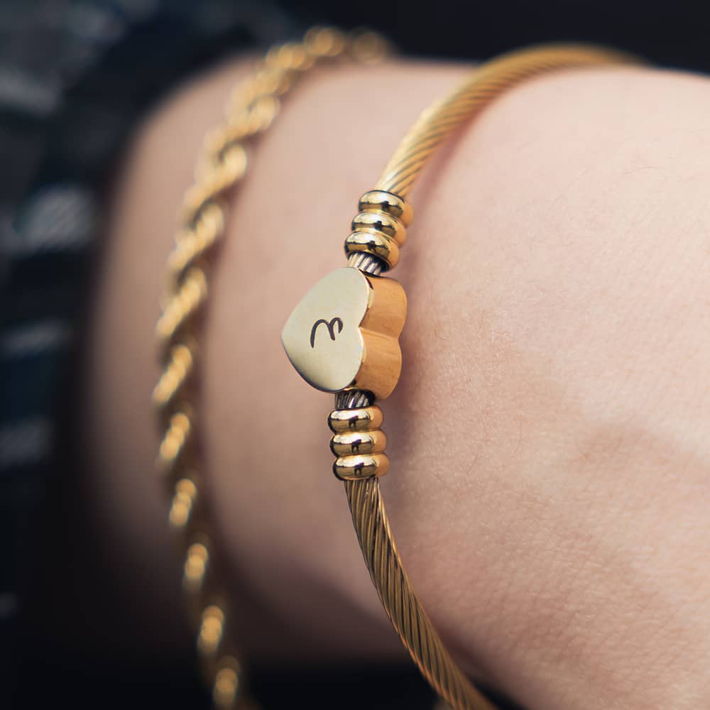 woman wearing 18ct gold plated elastic gold bangle with an engraved arabic initial on heart