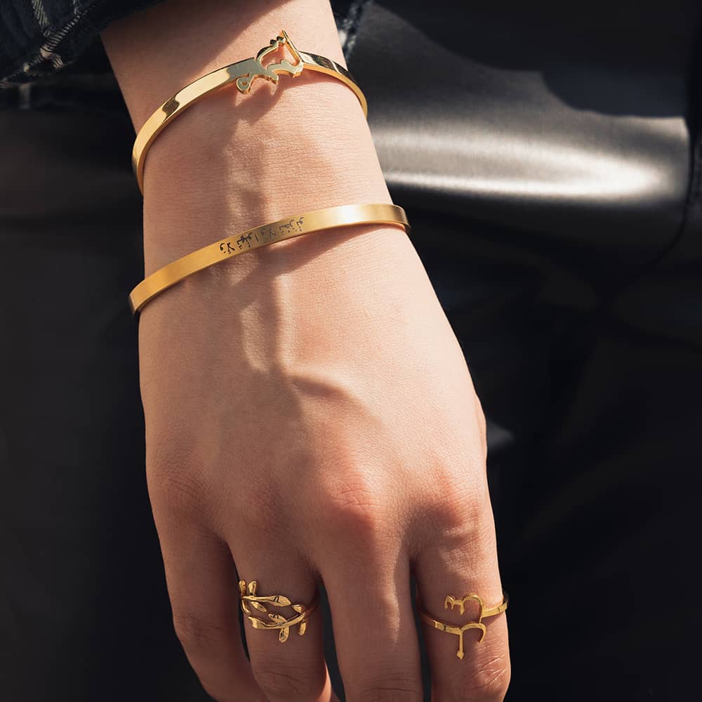 woman wearing engraved gold custom cuff with arabic quote engraving