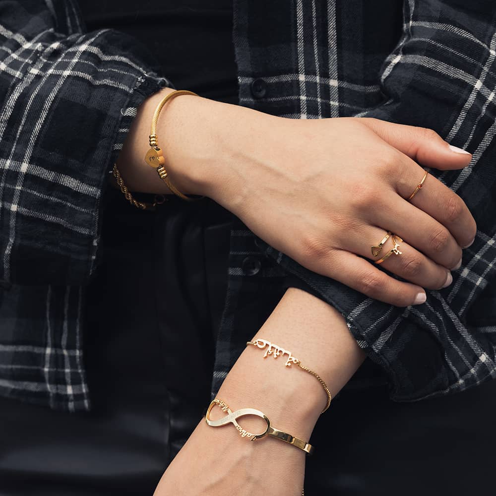 woman wearing 18ct gold plated jewellery including a personalised bangle in an infinity design for couples and personalised bracelet