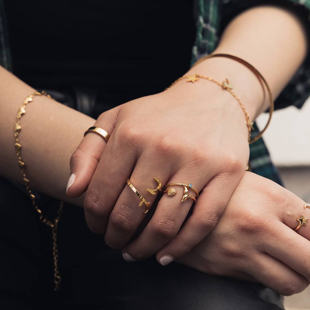 woman wearing 18ct gold plated personalised jewellery including a selection of rings and bracelets