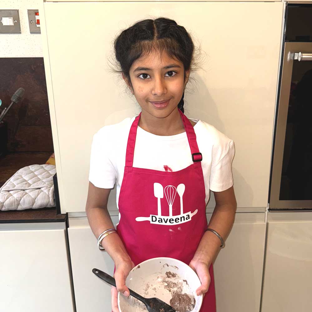 girl wearing pink personalised name apron while baking in the kitchen