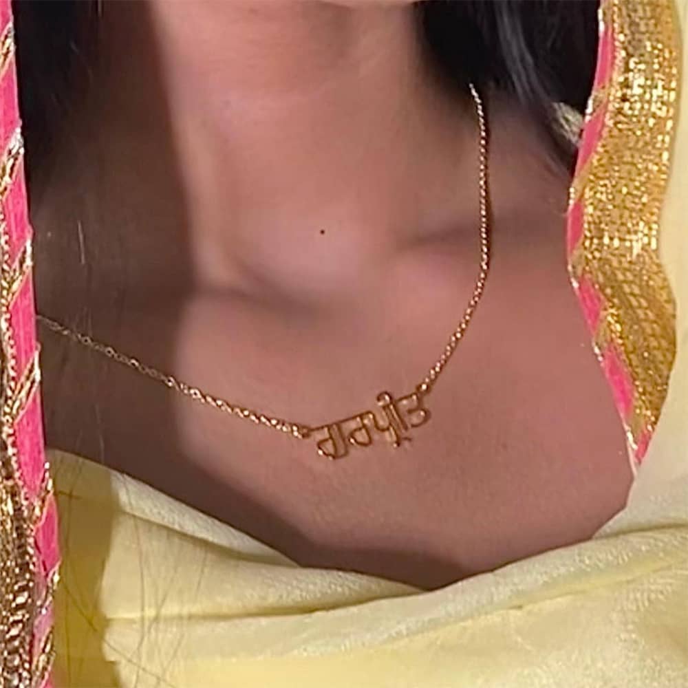 Close-up of Gurpreet's neck showing detailed Punjabi name necklace in gold