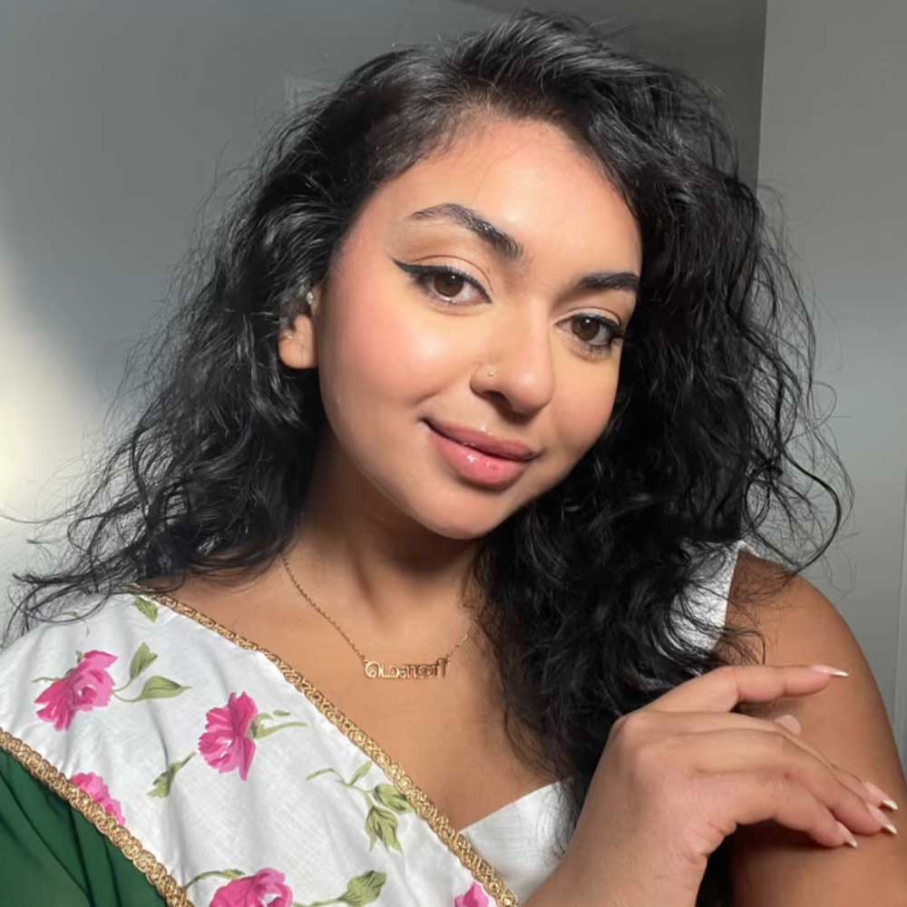 Influencer Melani wearing the Tamil necklace with a white floral saree