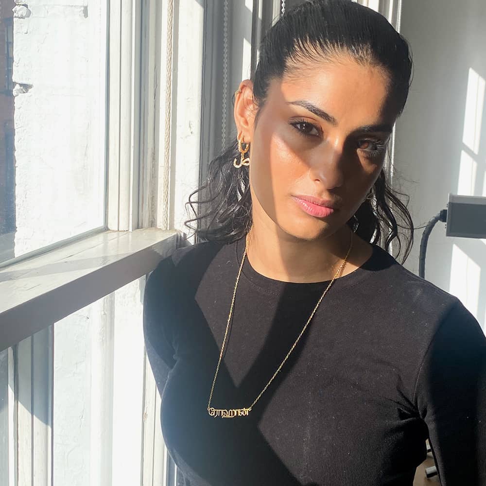 Eleisha wearing the Tamil Name Necklace by the window in soft sunlight