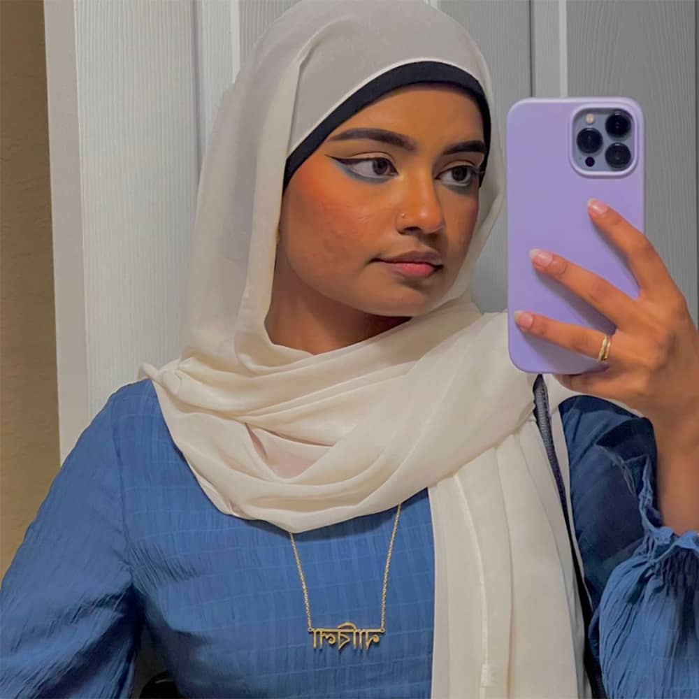 Influencer Nabila wearing Bangla name necklace in gold with blue dress and white hijab