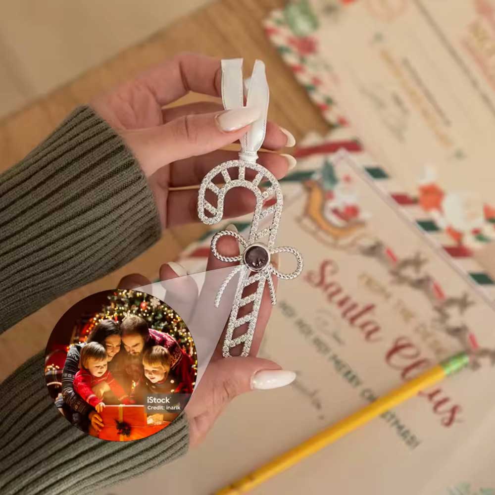 woman holding christmas ornament in shape of candy cane with hidden family photo