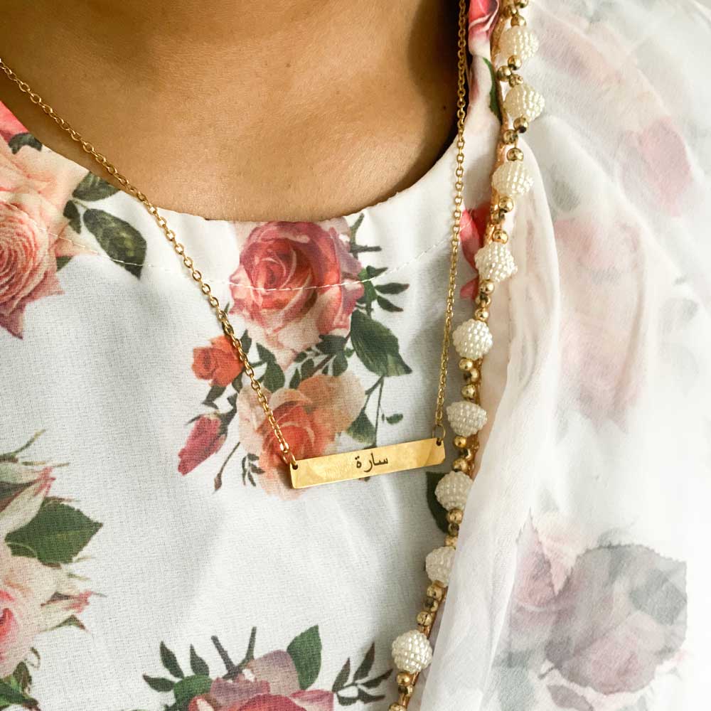 closeup of woman wearing gold engraved bar necklace with arabic name engraved wearing a saree