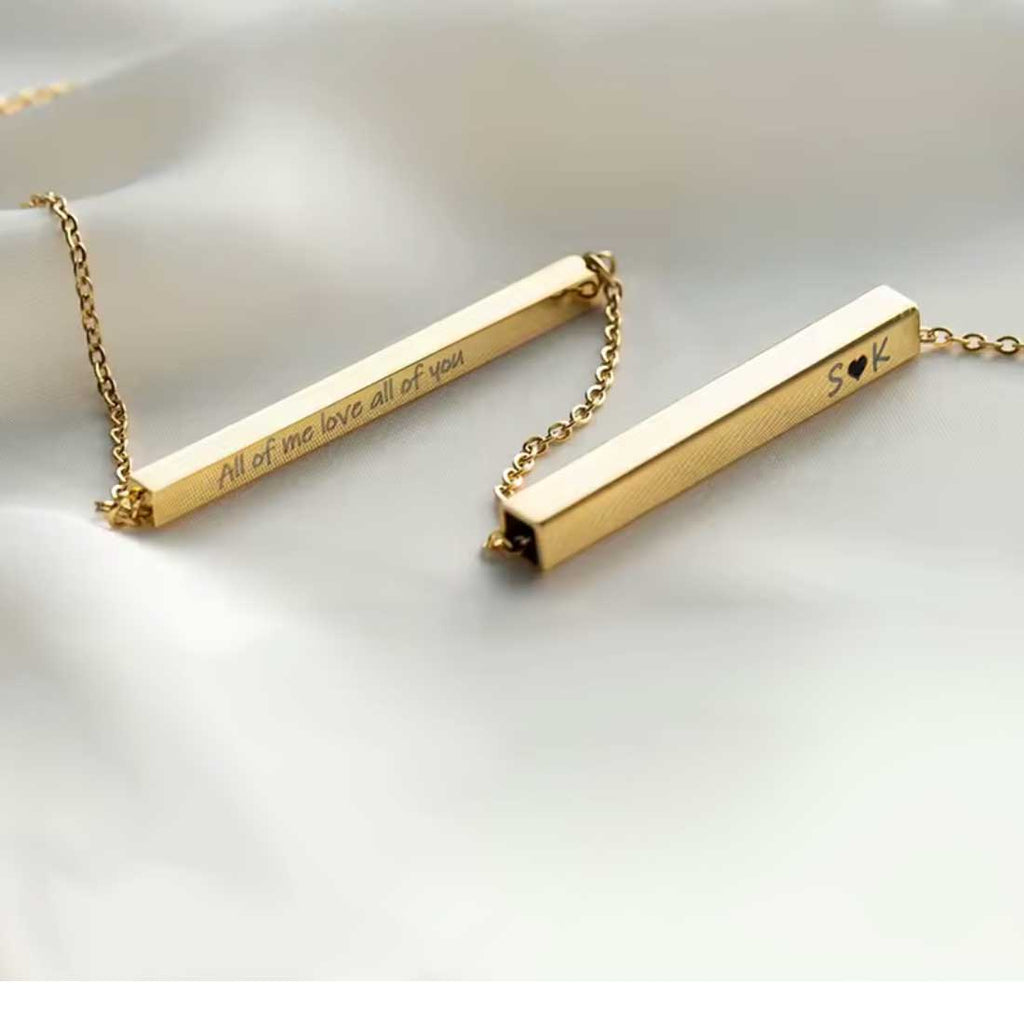Gold bar necklaces with engraved text on a light background