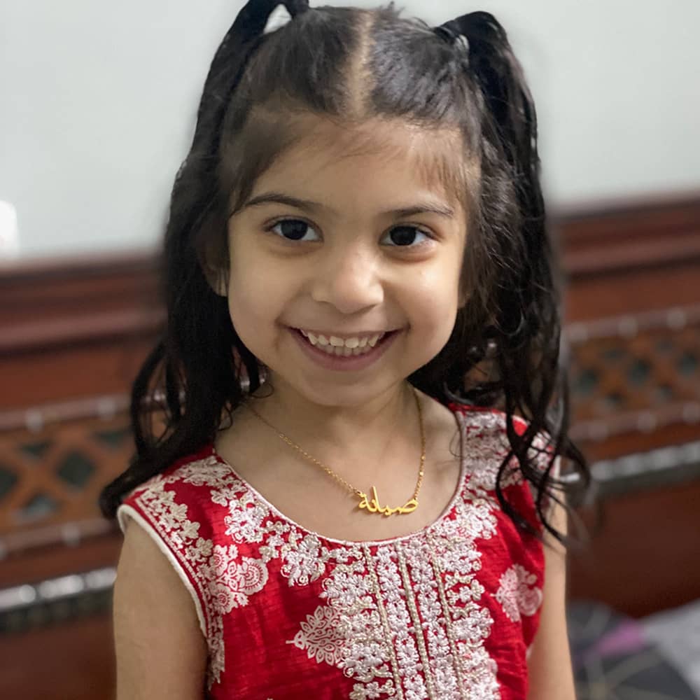 4 year old child wearing a custom name necklace in arabic with a child's length to fit perfectly