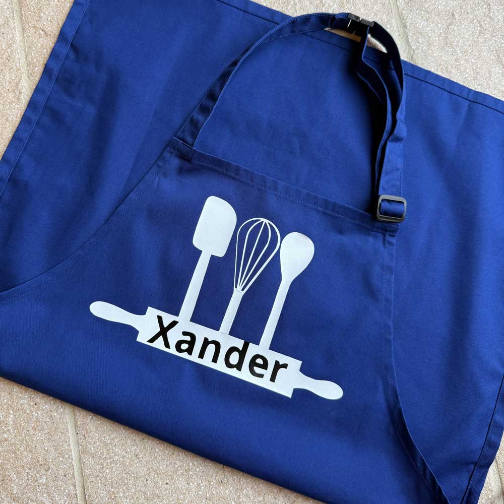 blue childrens apron with personalised name in english and rolling pin and whisk design