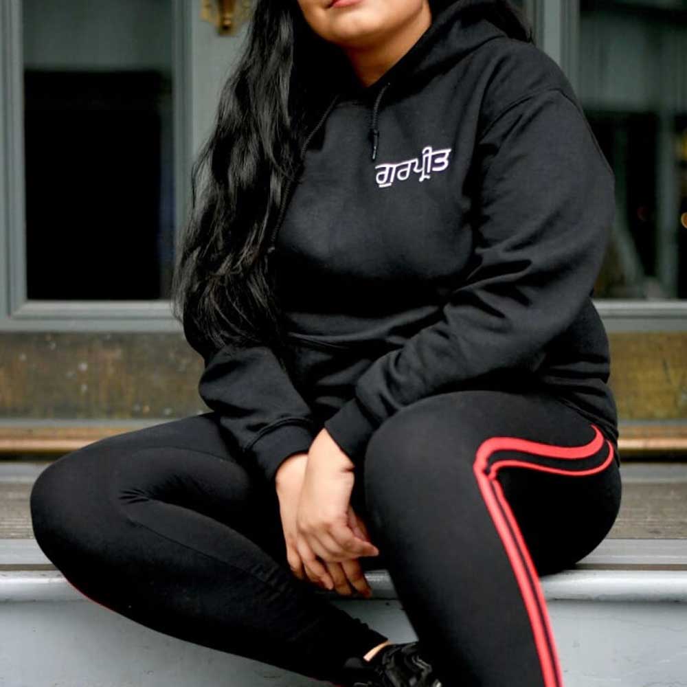 Girl wearing black personalised Punjabi hoodie with metallic gold Gurmukhi text