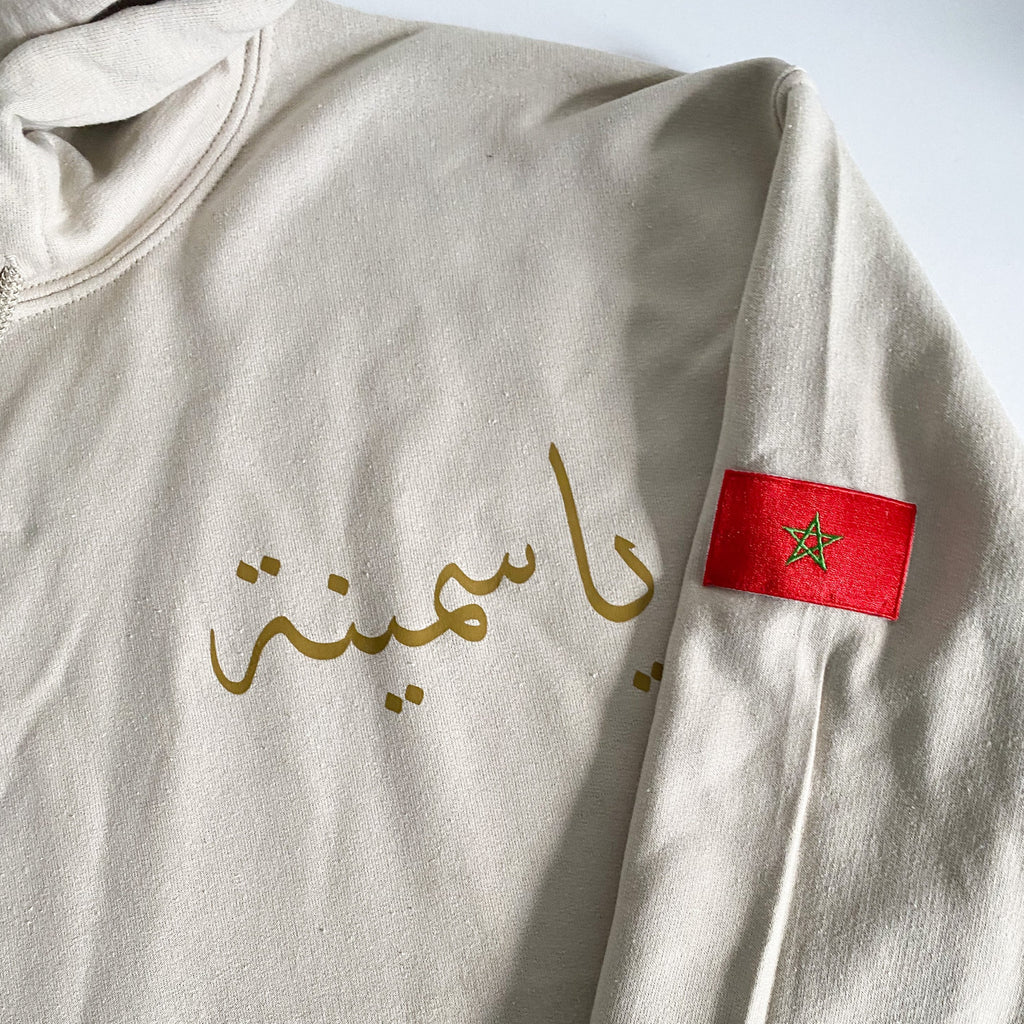 sand hoodie with metallic gold Arabic name on left chest and morocco flag on upper left sleeve