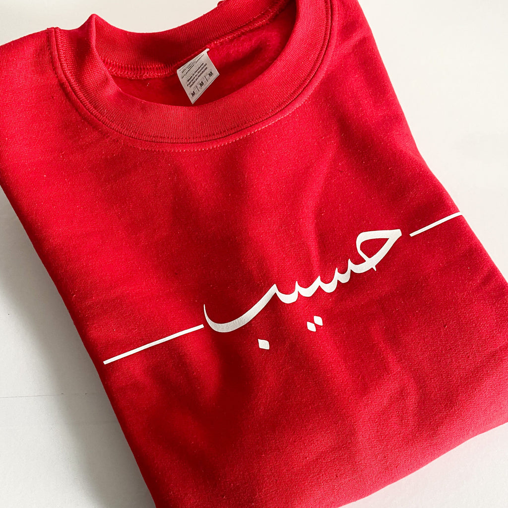 red hoodie with white Arabic name and design across the front chest