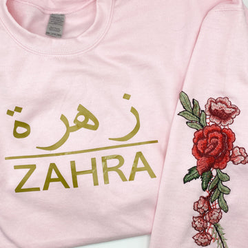 light pink hoodie with metallic gold Arabic and English name with red floral sleeve embroidery