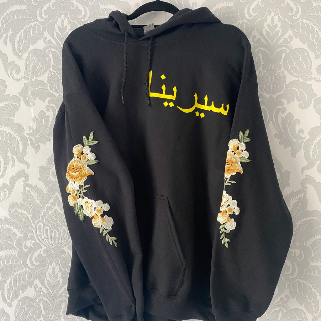 black hoodie with yellow arabic name on left chest and yellow floral sleeve embroidery