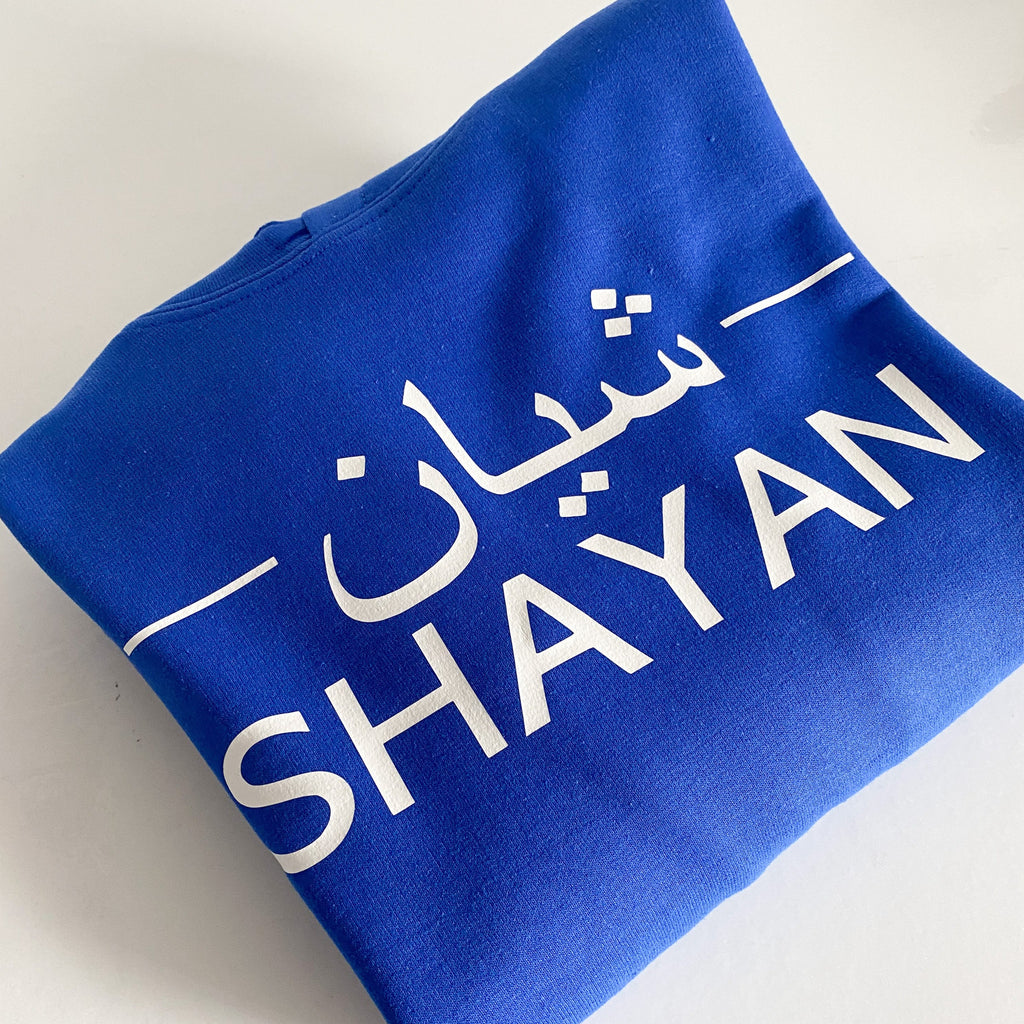 royal blue hoodie with white Arabic and English name design printed across the chest